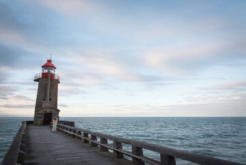 Le phare de Fécamp. Un phare au bord de l'océan. Un ponton menant à un phare.