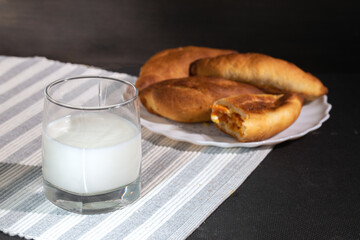 hot homemade patties from oven with glass of milk on table. Rustic traditional pastries.