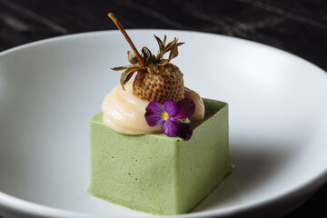 Panacotta dessert with green color with pickled strawberries - 361940356