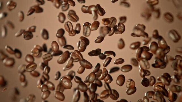 Super Slow Motion Shot of Crashing Coffee Beans on Brown Gradient Background at 1000fps.