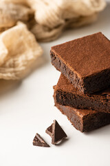 selective focus of delicious brownie pieces with dark chocolate on white background