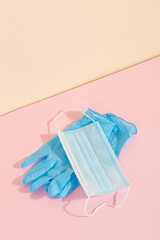 Blue medical gloves and mask on a yellow pink background. The concept of protection against disease. Copy space.