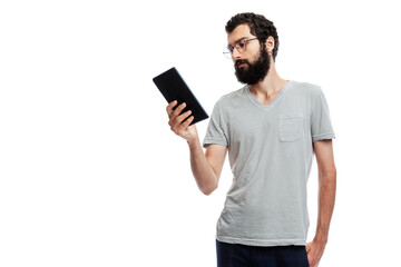 Stylish young man with a beard and glasses with a tablet in his hand. Training, online communication, social networks and blogging. Isolated on a white background. Space for text.