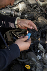 Fototapeta na wymiar Car mechanic repairs car breakdowns, changes filter and changes spark plugs, ignition coil tip