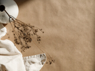 Minimalist kraft paper  background with a ceramic vase and dry grass.