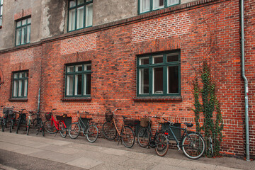 Fototapeta na wymiar Row of bikes near brick facade of building on urban street, Copenhagen, Denmark