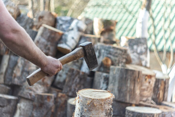 Man holding an industrial ax. Ax in hand. A strong man holds an ax in his hands against the background of chainsaws and firewood. Strong man lumberjack with an ax in his hand.