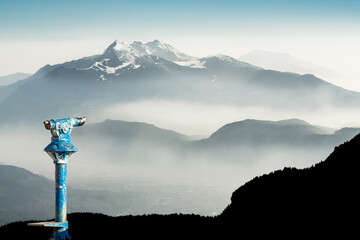 Public binoculars and Mountain Silhouettes at Sunrise. Foresight and vision for new business concepts and creative ideas. Alps, Trentino, South Tyrol, Italy.