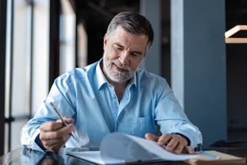 Businessman sitting in a business center restaurant, looking through contract.