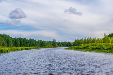 Fototapeta premium Picturesque summer landscape with northern river and forest in summer cloudy day. Travelling and discovering distant places of Earth. View from floating boat. Chernaya river, Karelia, Russia