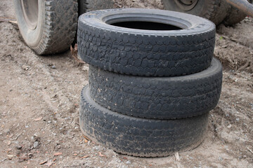 Obraz premium Three old tires stacked, close-up of a truck tire. Environmental pollution. Dump tires.
