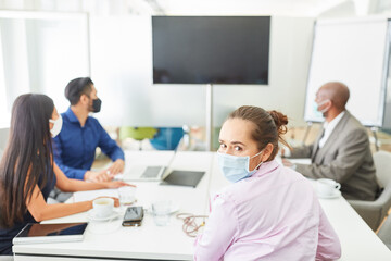 Fototapeta premium Business Frau mit Mundschutz wegen Covid-19 im Meeting