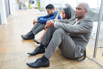Frustrierte Geschäftsleute sitzen auf dem Fußboden im Büro