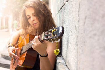 Beautiful curly brunette hair hippie girl playing guitar in the street. Freedom and free lifestyle....