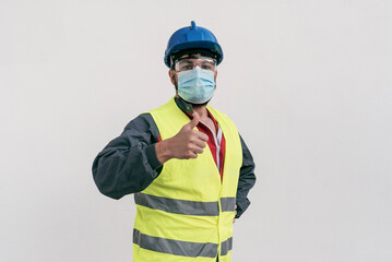 Construction worker portrait on white wall posing with face mask covid -19 prevention