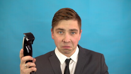 Naklejka premium Businessman with a hairdresser. A man in a suit on a blue background is preparing for a haircut.