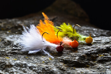 Group of colorful jig streamer made of feathers on gray stone
