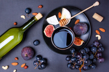 Bottle of wine, blue grapes, cheese and figs on a gray background. View from above
