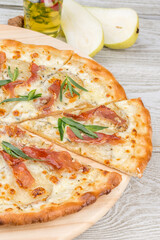 Pizza with bacon and herbs on a wooden plate