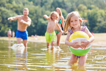 Little girl with a ball is playing in the sea