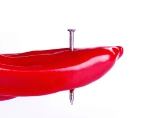 Nail piercing through a red chilli