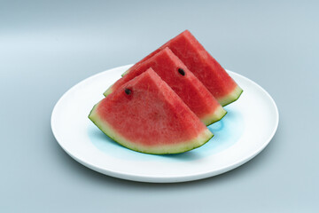 Several pieces of watermelon are placed in a white porcelain dish. Watermelon is placed in a white...
