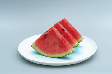 Several pieces of watermelon are placed in a white porcelain dish. Watermelon is placed in a white dish