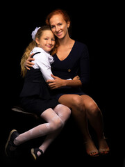 Mom and little daughter studio portrait.On black background