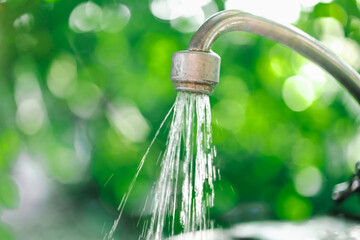 The flow of water from the tap with blurred background bokeh holiday season and the kitchen at the...