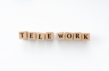 A wooden block with the word tele work written on it on a white background