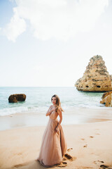 Fototapeta na wymiar Beautiful woman on the beach. Single girl in long dress. Woman walking barefoot on white sand of tropical island.