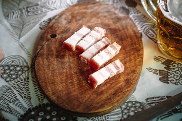 Pieces of lard with meat lie on a wooden Board, the harsh country style of elderly cottagers