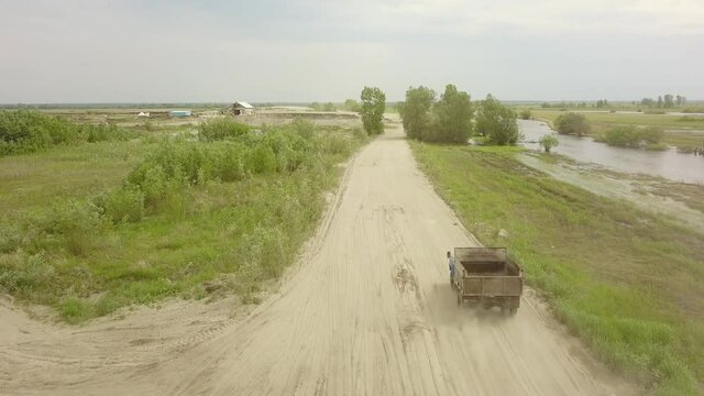 A flying camera shoots a truck passing in the fields below.