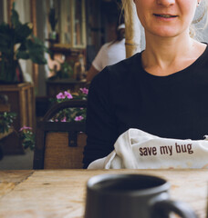young woman man drinking coffee in cafe, 
Caucasian woman sitting at the table with shopper bag, beautiful happy girl in cafe, eco friendly concept