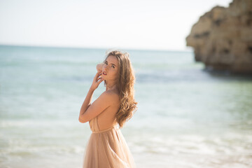 Fototapeta na wymiar Young female on beach wearing elegant dress. Beautiful Summer Woman on the Beach
