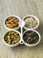 Nut and seed selection in four bowls with white spoon