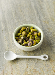 Pistachios in green bowl with white spoon