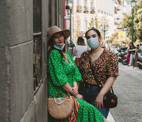 Two girls Friends looking at camera wearing medical mask to prevent spread of Covid-19 infection. People need to wear a mask in public places. Friends with a mask during the new normal.