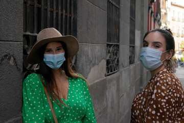 Two girls Friends looking at camera wearing medical mask to prevent spread of Covid-19 infection. People need to wear a mask in public places. Friends with a mask during the new normal.