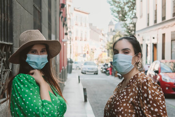 Two girls Friends looking at camera wearing medical mask to prevent spread of Covid-19 infection. People need to wear a mask in public places. Friends with a mask during the new normal.