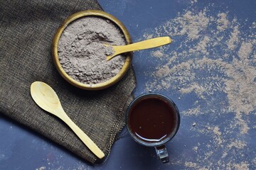 Wooden bowl with cocoa powder, chocolate in glass cup and wooden spoons, space for text