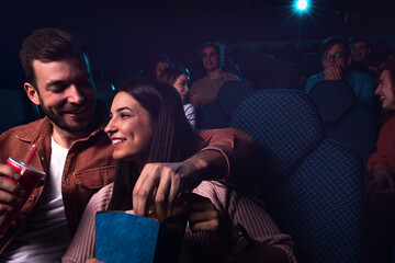 Group of cheerful people laughing while watching movie in cinema.