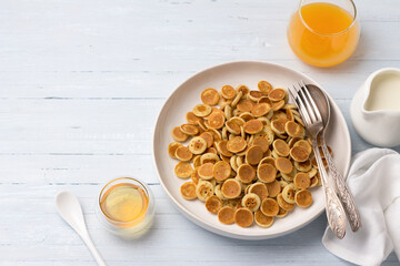 Plate of Mini Pancakes cereals with honey, cream and fresh orange juice on a light blue background. trendy food. homemade breakfast. top view. space