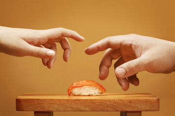 Deux mains essayant de prendre un sushi