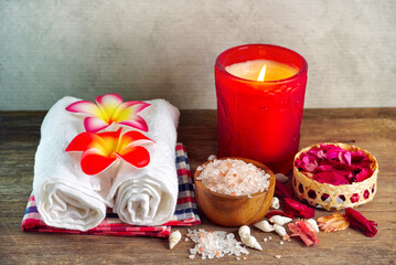 Obraz na płótnie Canvas Himalayan salt and towels decorate and aroma candle decorate with red flower and small shell on the table, spa decoration concept.