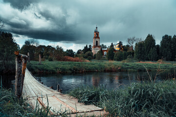 An old stone Church by the river Bank against a gloomy overcast sky