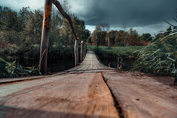 An old wooden bridge over a river that opens into a grassy field