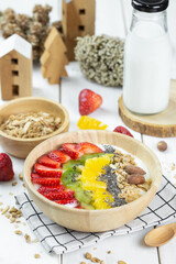 One big bowl of natural yogurt with strawberry, kiwi, almond, pineapple serve on wood table and milk.