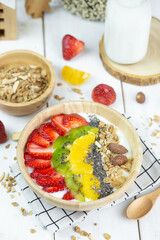 One big bowl of natural yogurt with strawberry, kiwi, almond, pineapple serve on wood table and milk.
