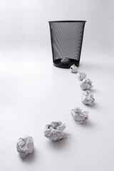 Crumpled papers trailing to a dustbin